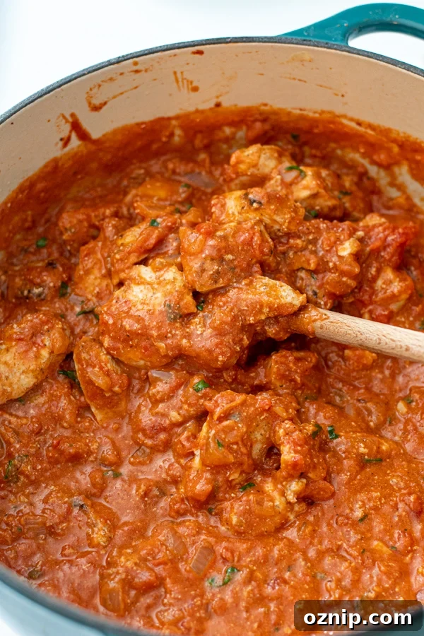 Chicken added to tikka masala sauce in a large dutch oven.