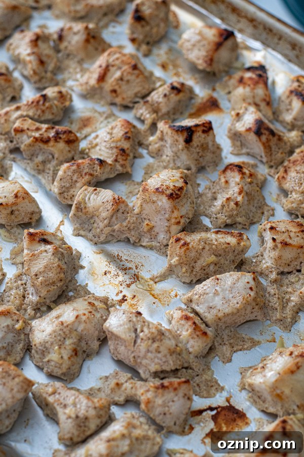 Freshly broiled chicken on a sheet pan ready to be added to tikka masala sauce.