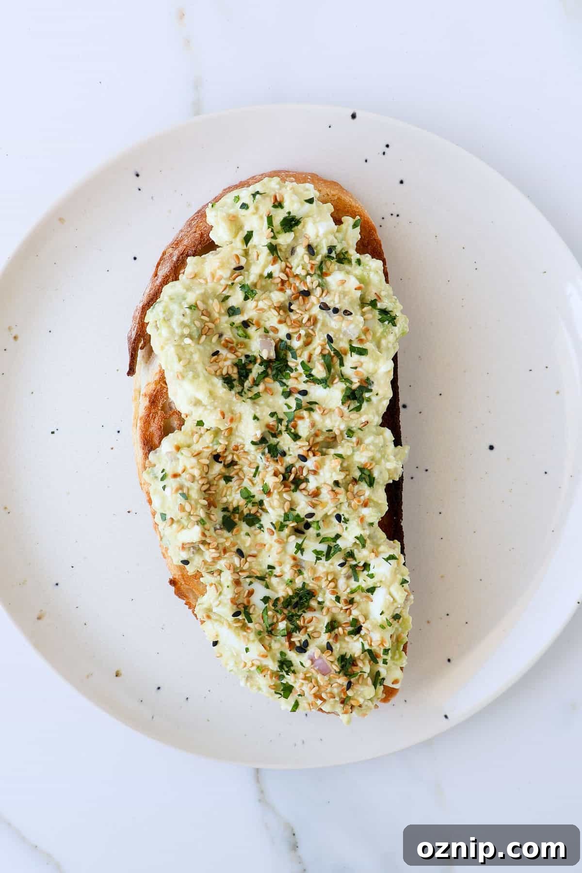 Cottage Cheese and Avocado Toast Recipe for Brunch 2 Cottage cheese avocado toast with sesame seeds and parsley on top.