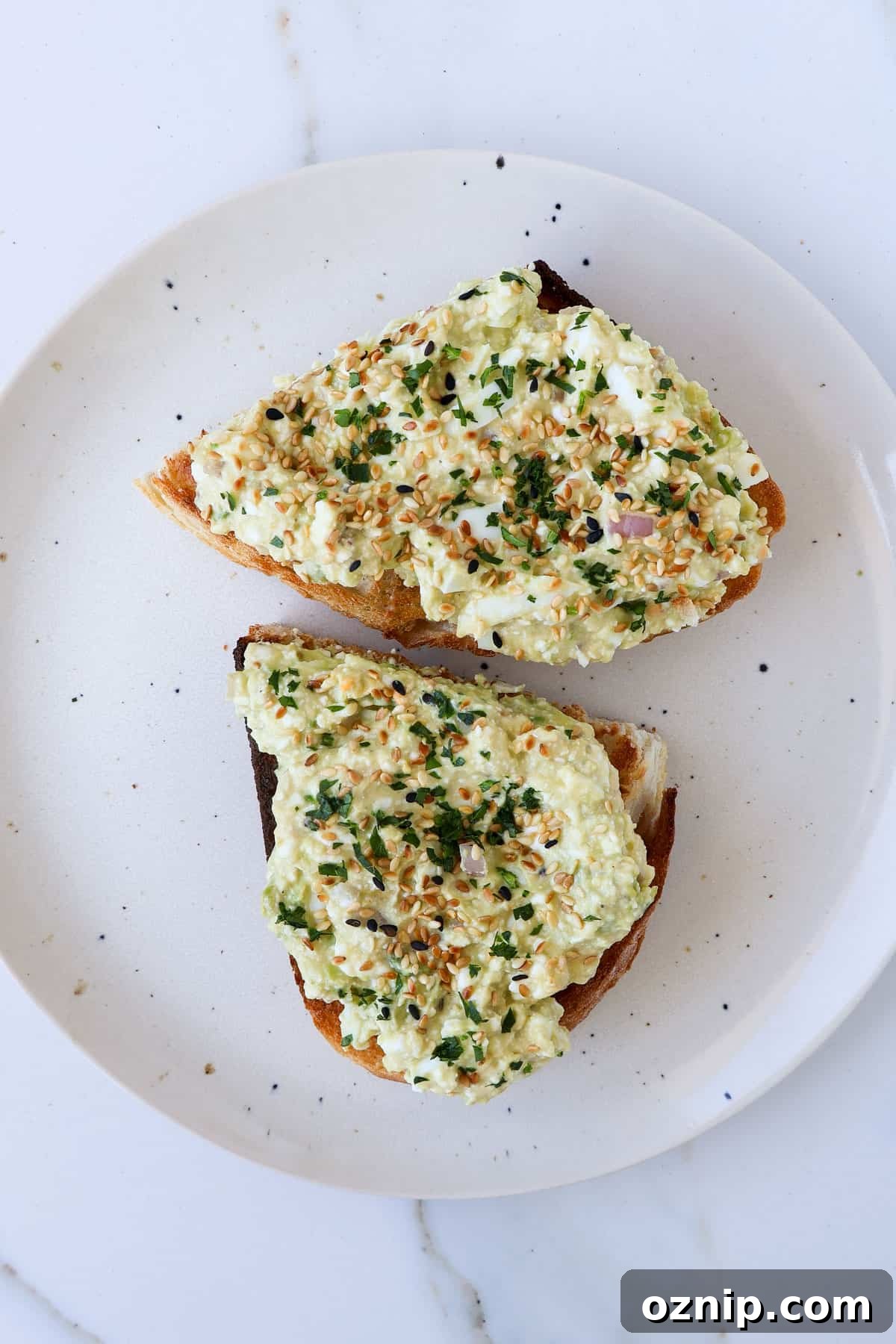 Cottage Cheese and Avocado Toast Recipe for Brunch 7 Cottage cheese avocado toast cut in half on a plate.