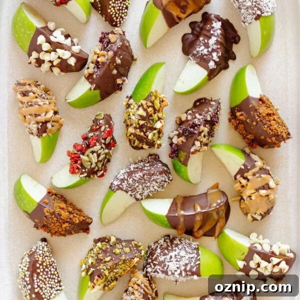 A variety of chocolate dipped apple slices on a cream colored serving platter.