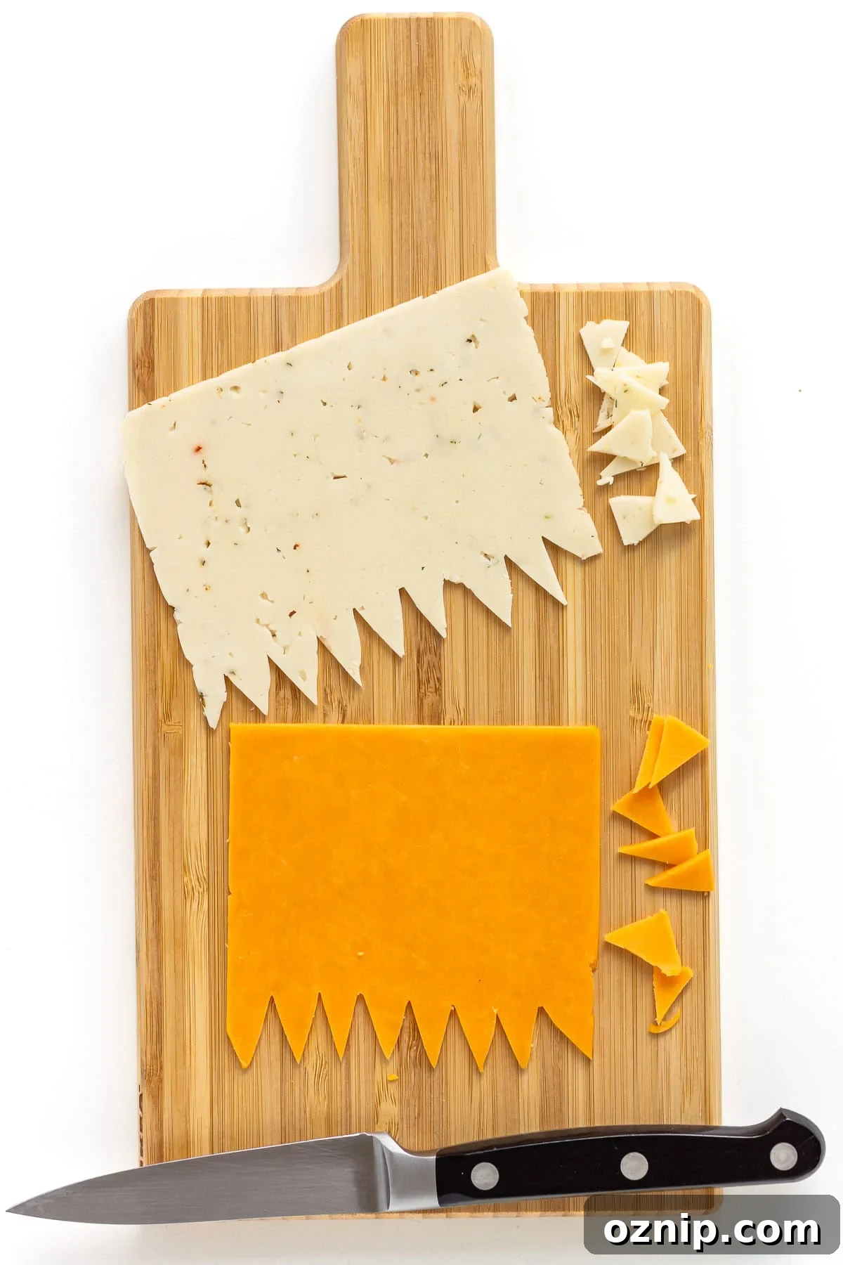Two cheese slices on cutting board with zigzag pattern cut out along one edge.