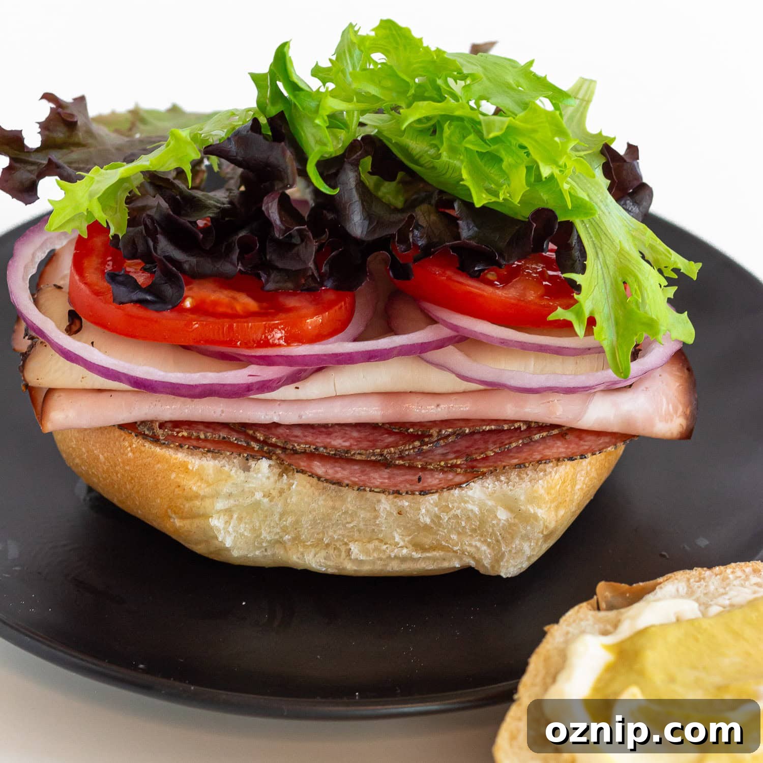 Sandwich being built on a kaiser bun with top off to the side.