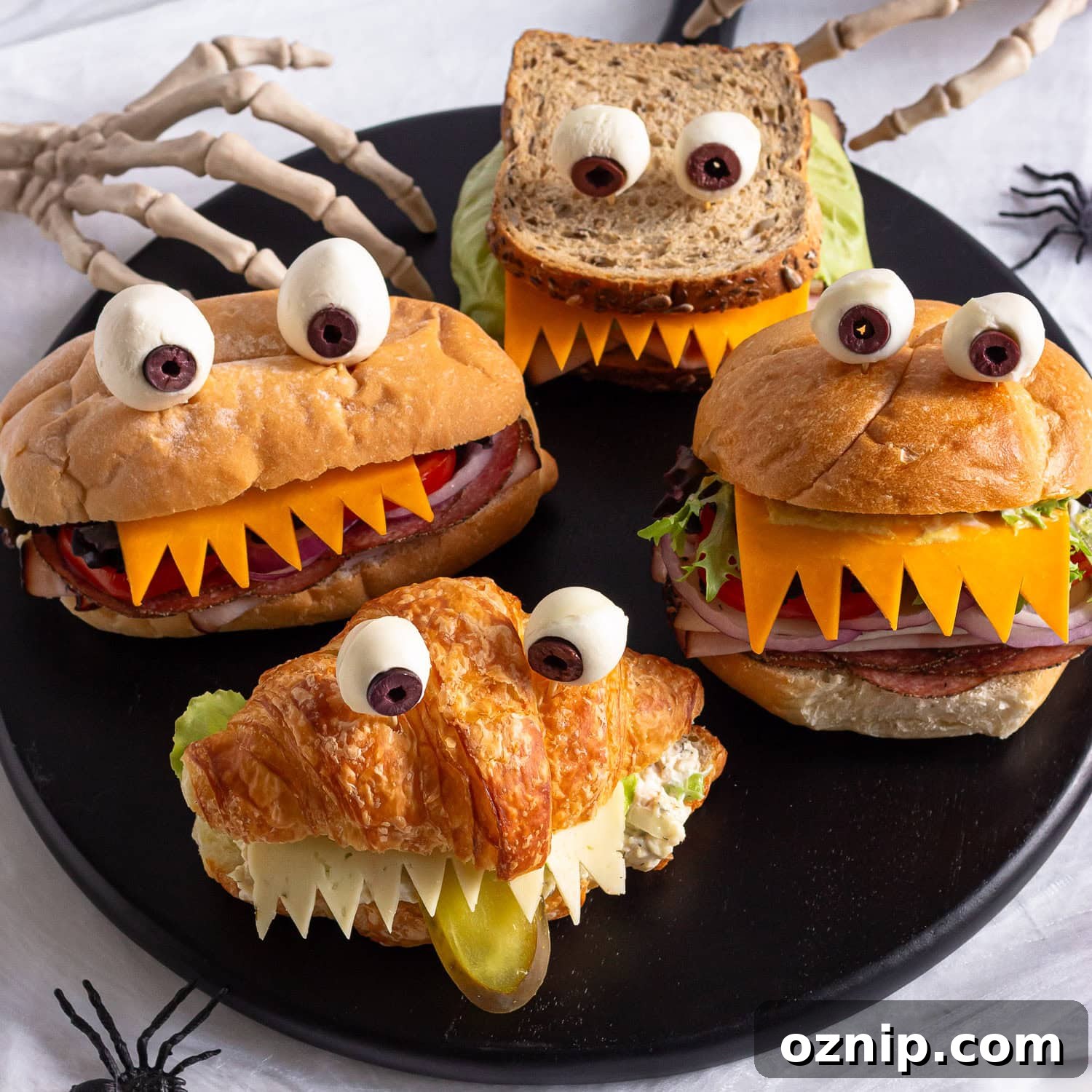 Halloween monster sandwiches on a black round serving board.