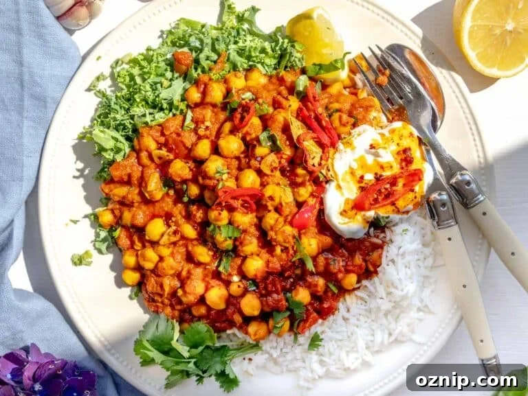 Chana masala served on a plate with kale, yogurt, and chili oil