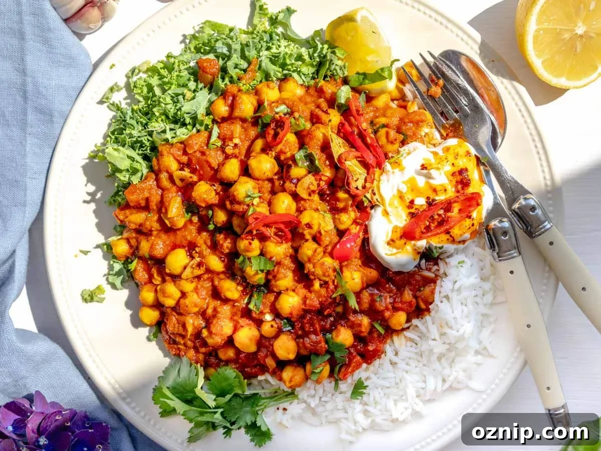 Chana masala served on a plate with kale, yogurt, and chili oil