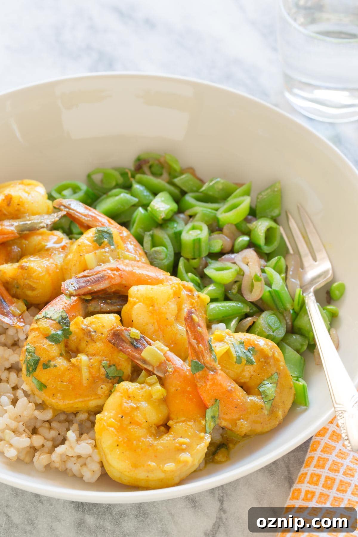 A bowl of coconut curry shrimp served over rice with snap peas.