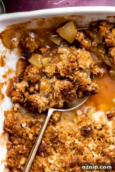 Baked apple crisp being served with a large spoon.
