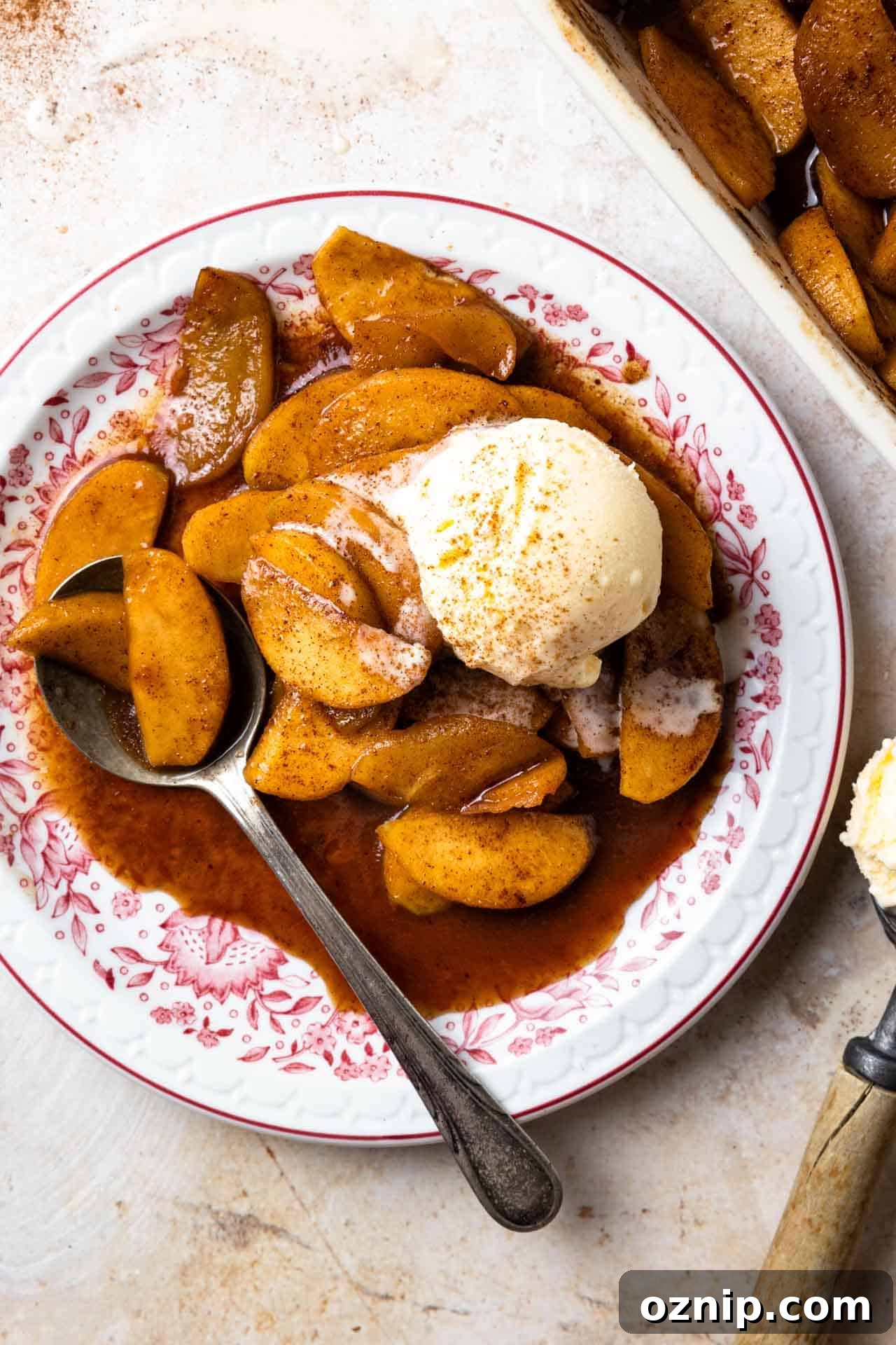 Bowl of baked apples served with a scoop of vanilla ice cream.
