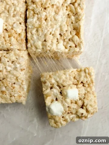 a close up of brown butter rice krispie treats with a marshmallow being pulled and stretched.