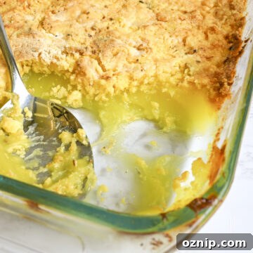 looking into a dish of lemon dump cake, with a pie filling layer and golden cake mix layer, spoon in baking dish.