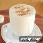 Smoothie in a glass topped with cinnamon and a banana slice.