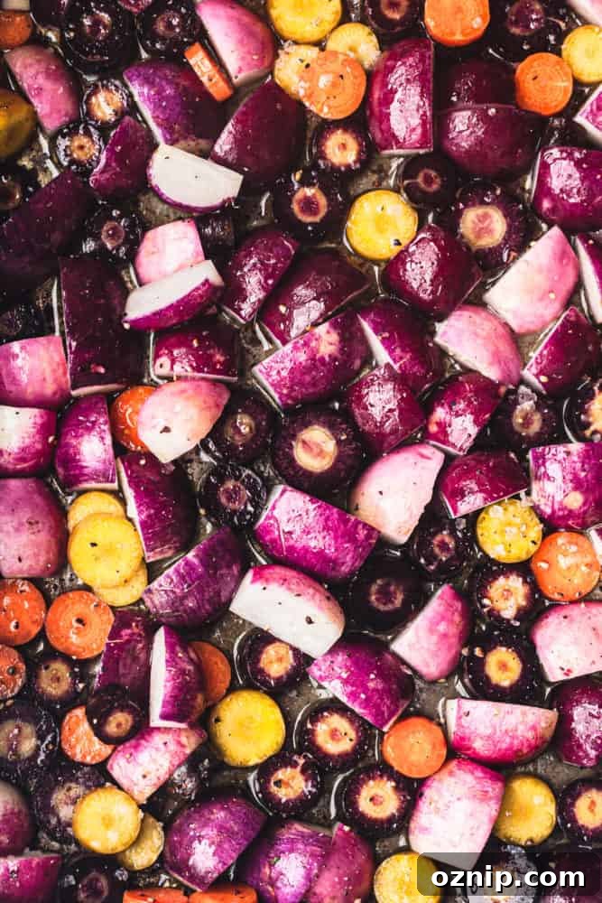Round radishes, quartered, and carrots sliced, on a baking sheet ready to be roasted and overhead shot.