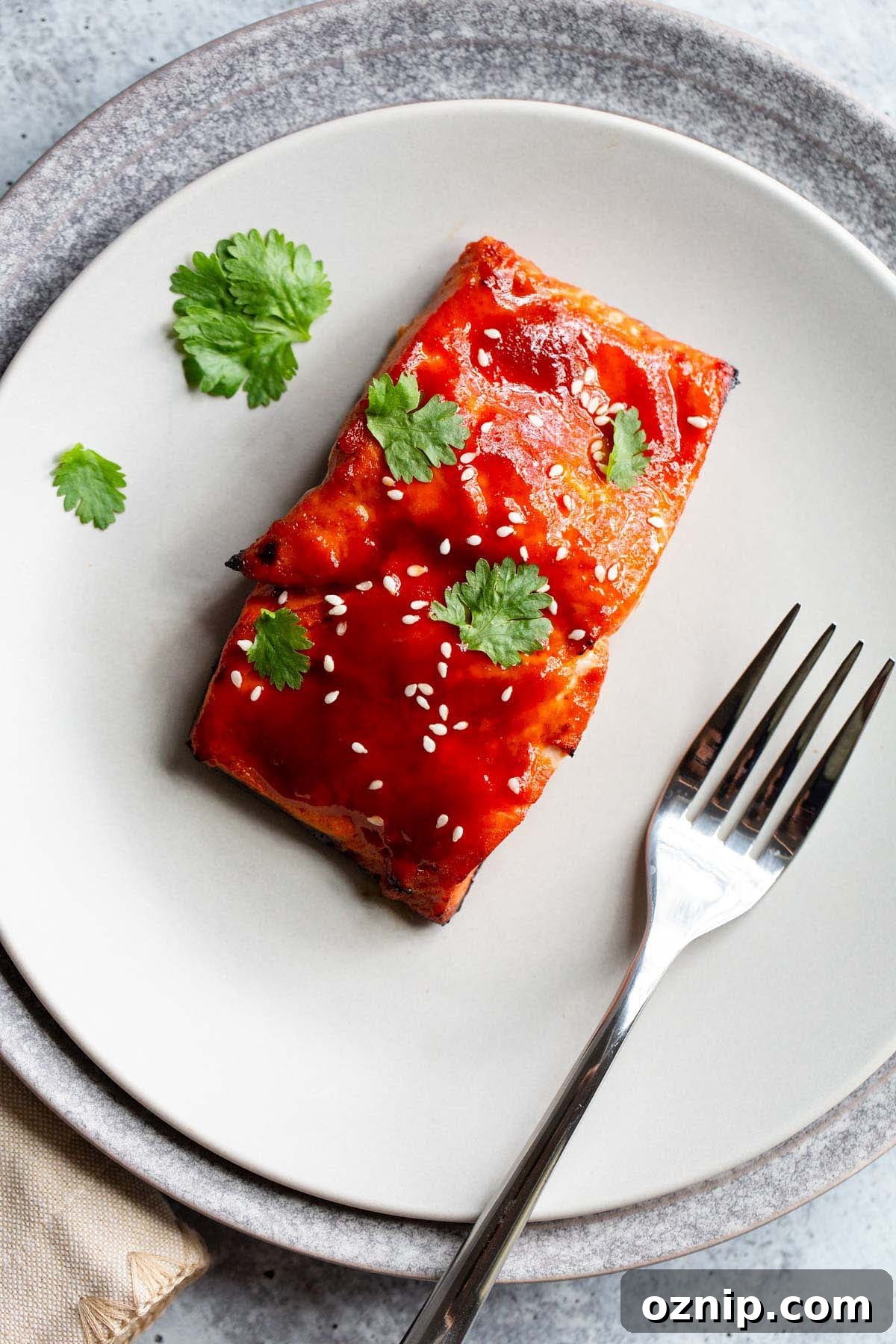 honey sriracha salmon on a plate with sesame seeds and cilantro.