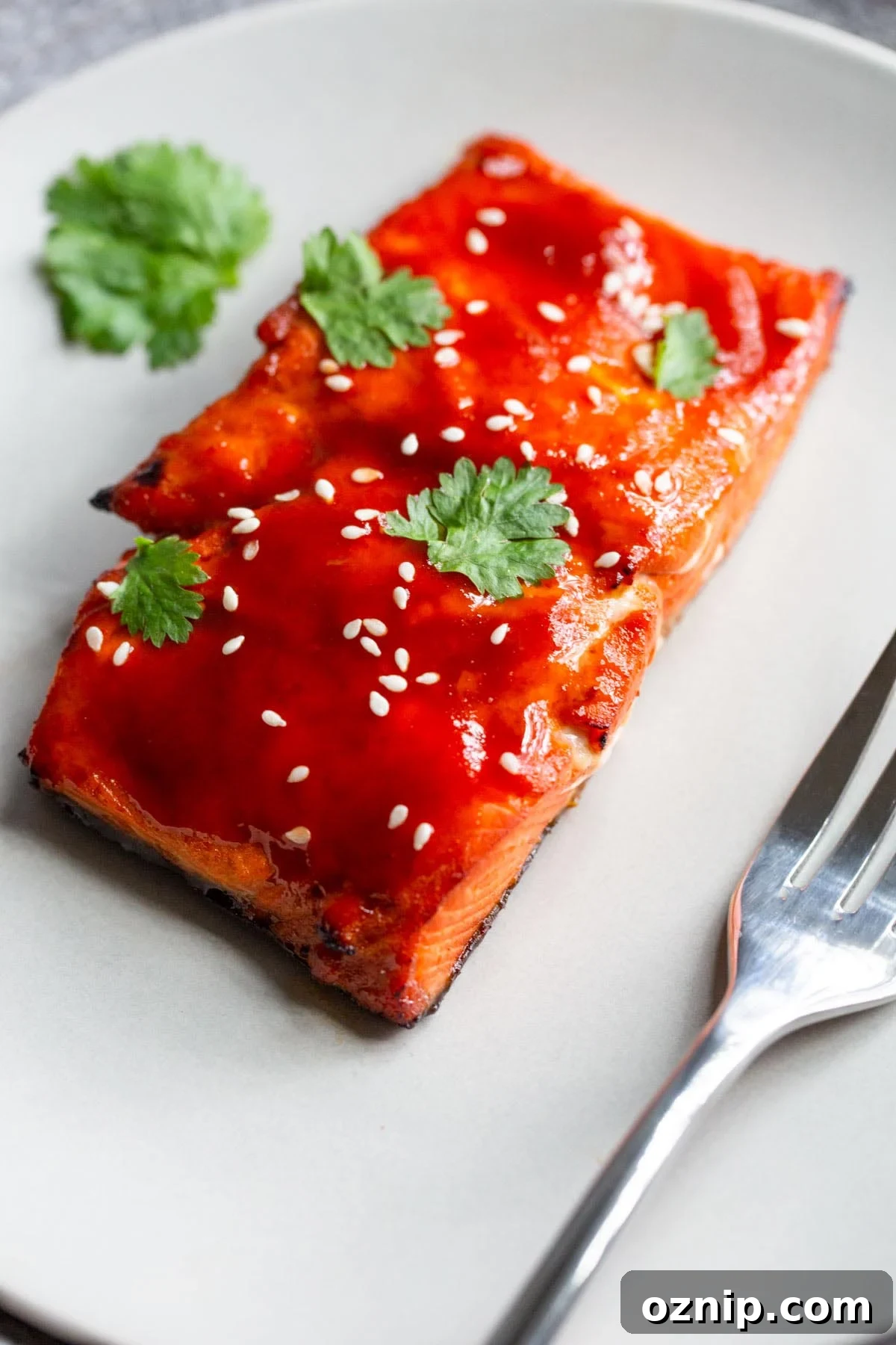 honey sriracha salmon on a plate with sesame seeds and cilantro.