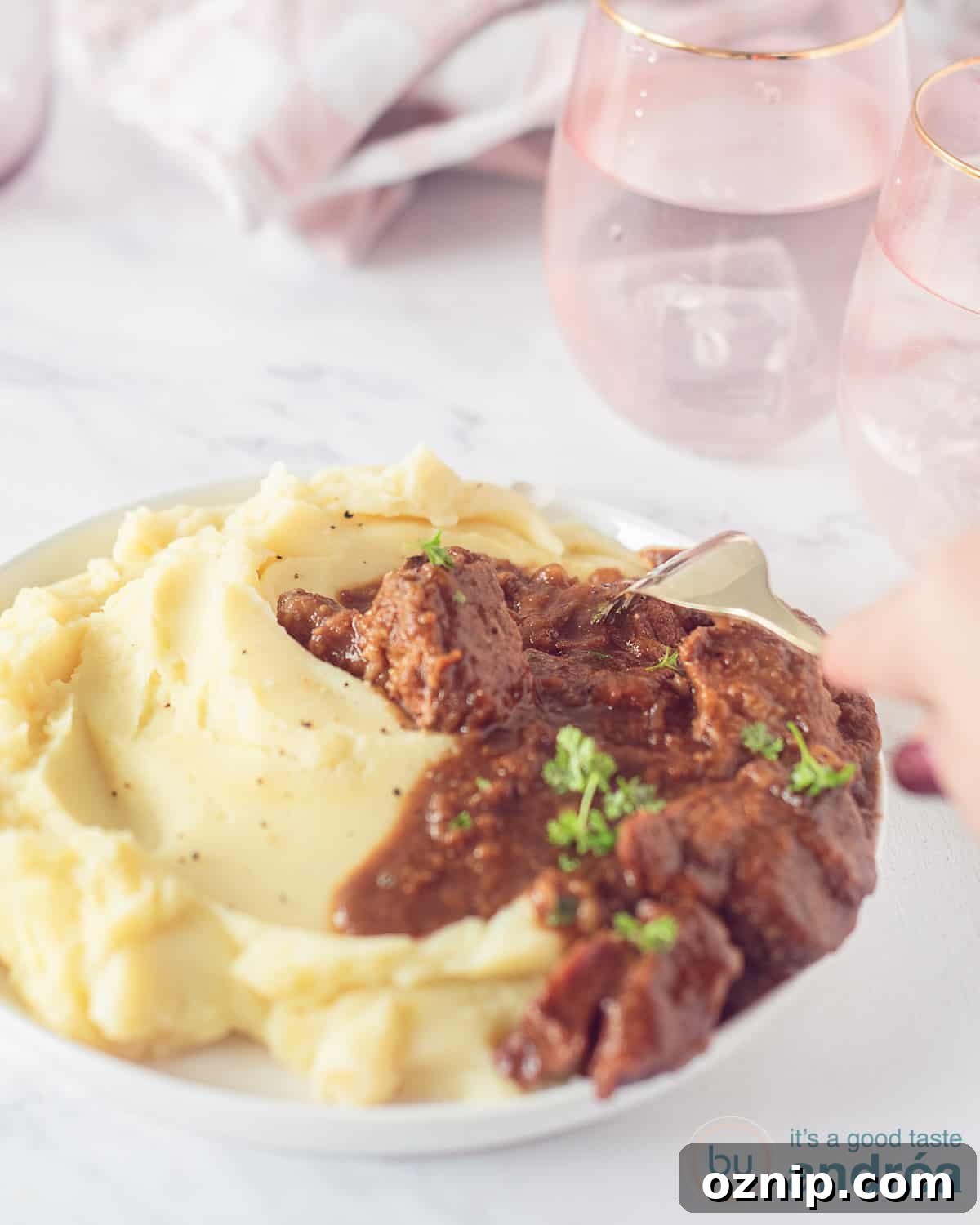 Slow-Cooked Beef Stew with Apple Butter and Speculoos 3 a white plate with mashed potatoes and beef stew with speculoos and apple butter