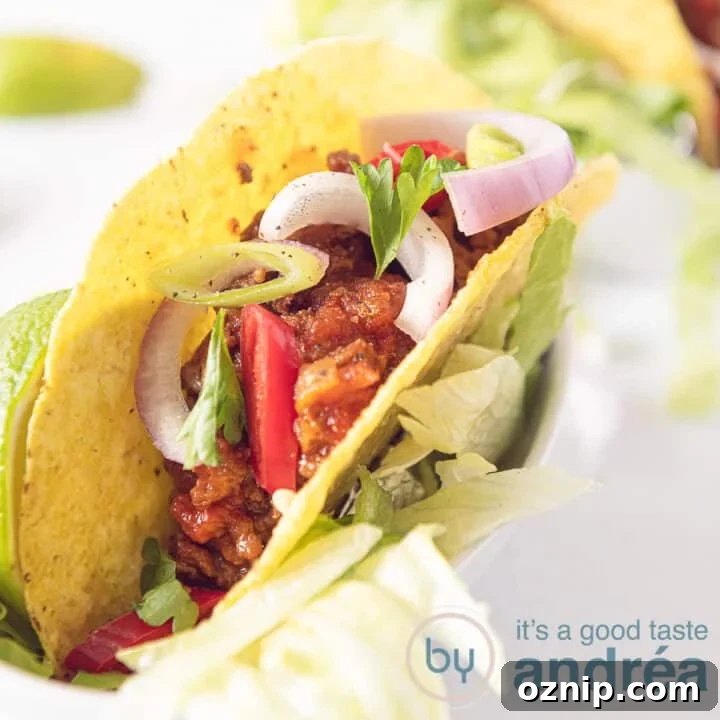 A taco filled with chili without beans. With a topping of onions and parsley on a white background