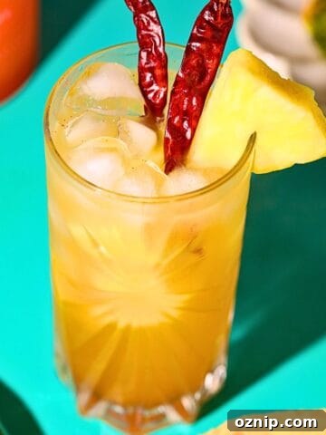 spicy pineapple lemonade in a glass on a table with a pineapple in the background.
