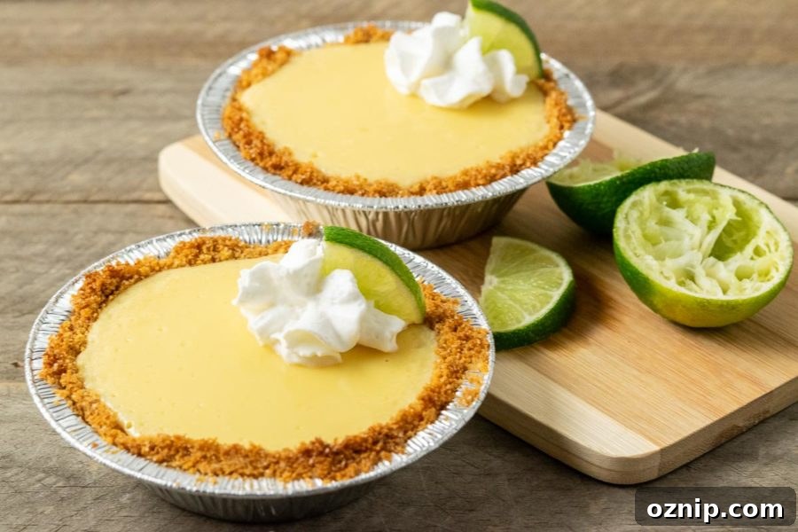 two mini yellow pies in graham crusts garnished with whipped cream and quarter lime slice.