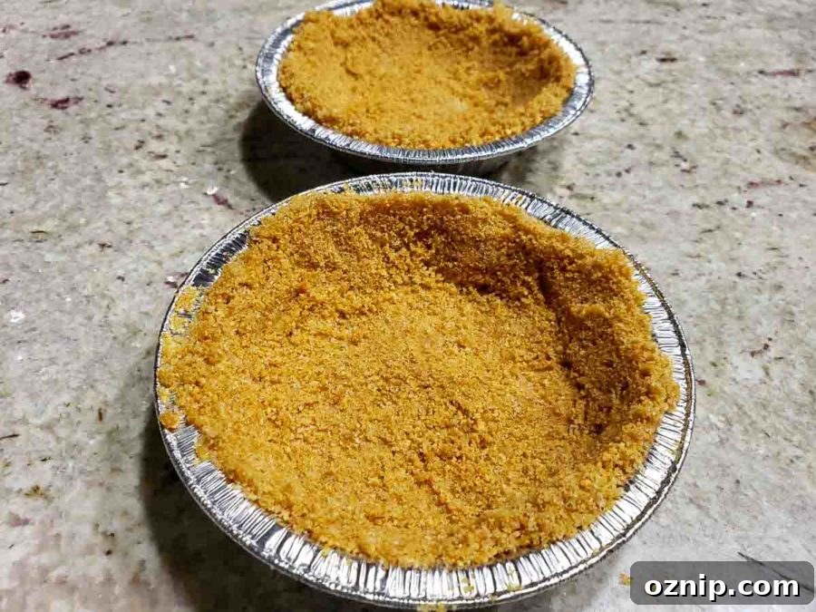 two small pie tins filled with graham crust mixture.