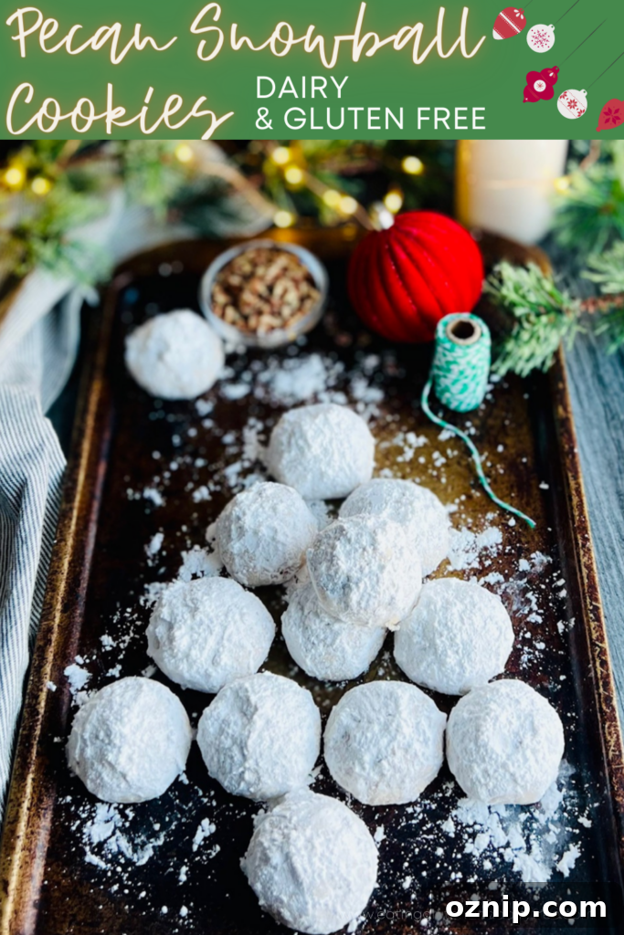 Pecan Snowball Cookies Recipe: Melt-in-Your-Mouth Holiday Treat 2 A dark baking sheet with white round cookies styled in the shape of a Christmas tree and white and green twine nearby.