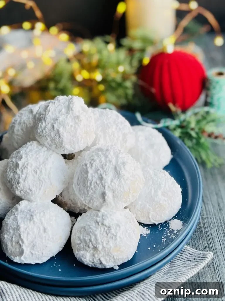 Pecan Snowball Cookies Recipe: Melt-in-Your-Mouth Holiday Treat 3 A small blue plate with several round, fluffy looking white cookies next to Christmas lights.