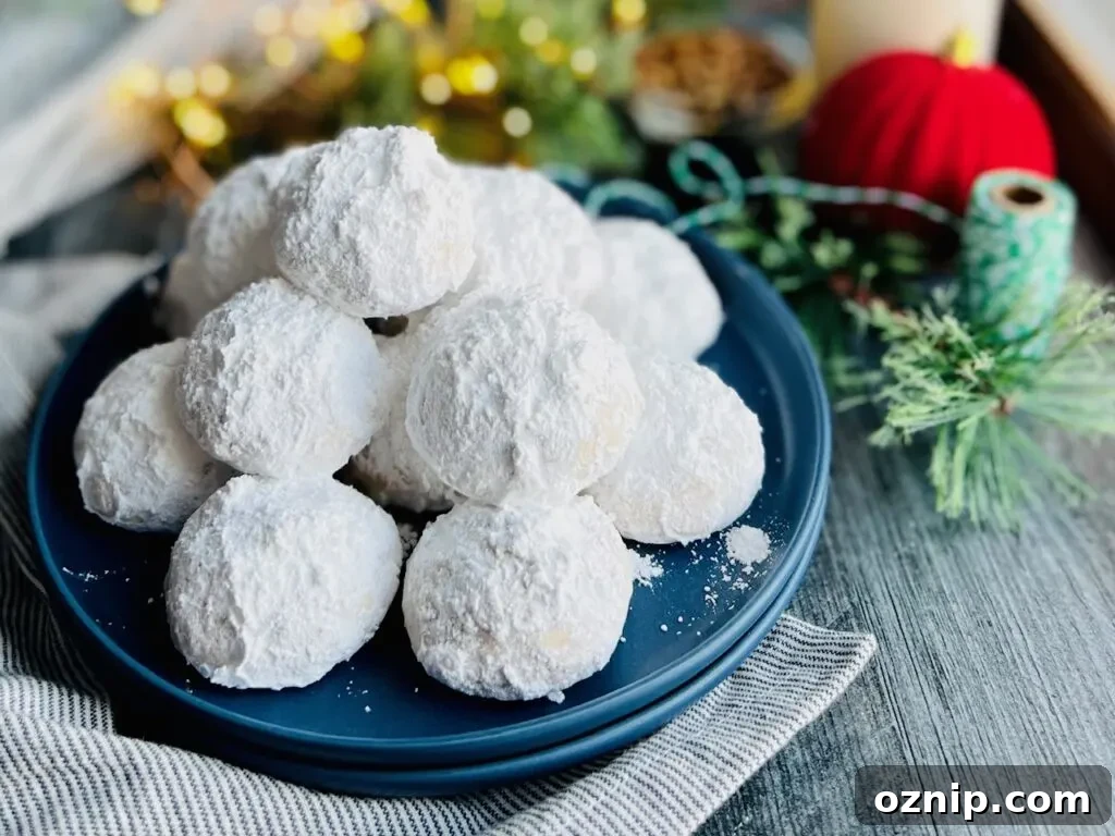 Pecan Snowball Cookies Recipe: Melt-in-Your-Mouth Holiday Treat 4 A small blue plate with several round, fluffy looking white cookies next to Christmas lights and Christmas decorations nearby.