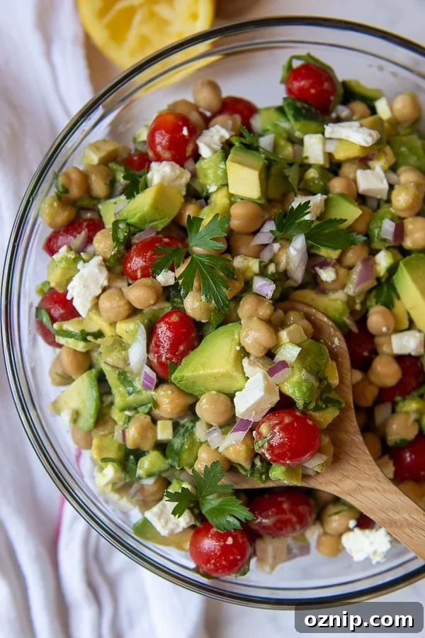 a wooden spoon holding up a serving of chickpea avocado salad