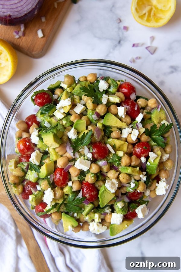 overhead shot of mediterranean chickpea salad with tomatoes, cucumbers, and avocado in the bowl
