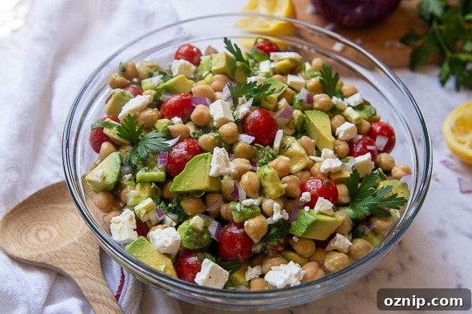 a large serving bowl of salad with a wooden serving utensil laying next to it