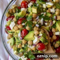 a wooden spoon holding up a serving of chickpea avocado salad