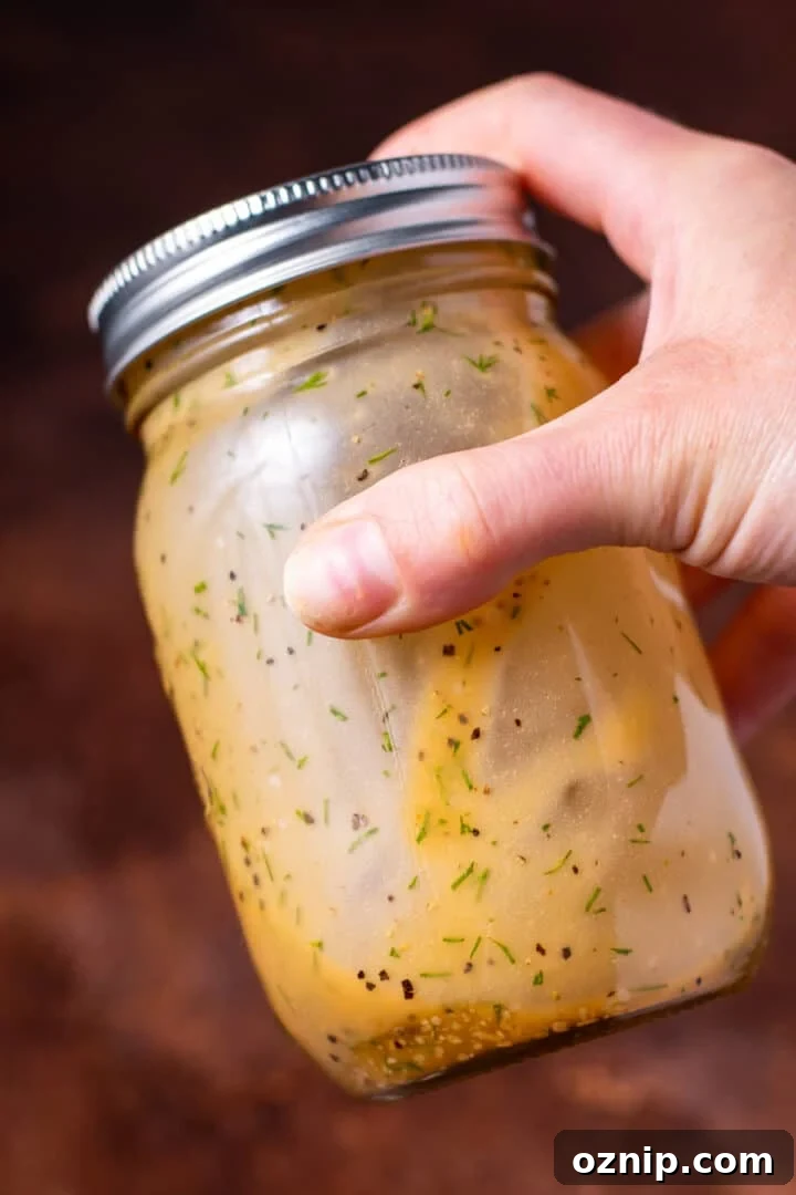 hand shaking together the dill vinaigrette in a mason jar