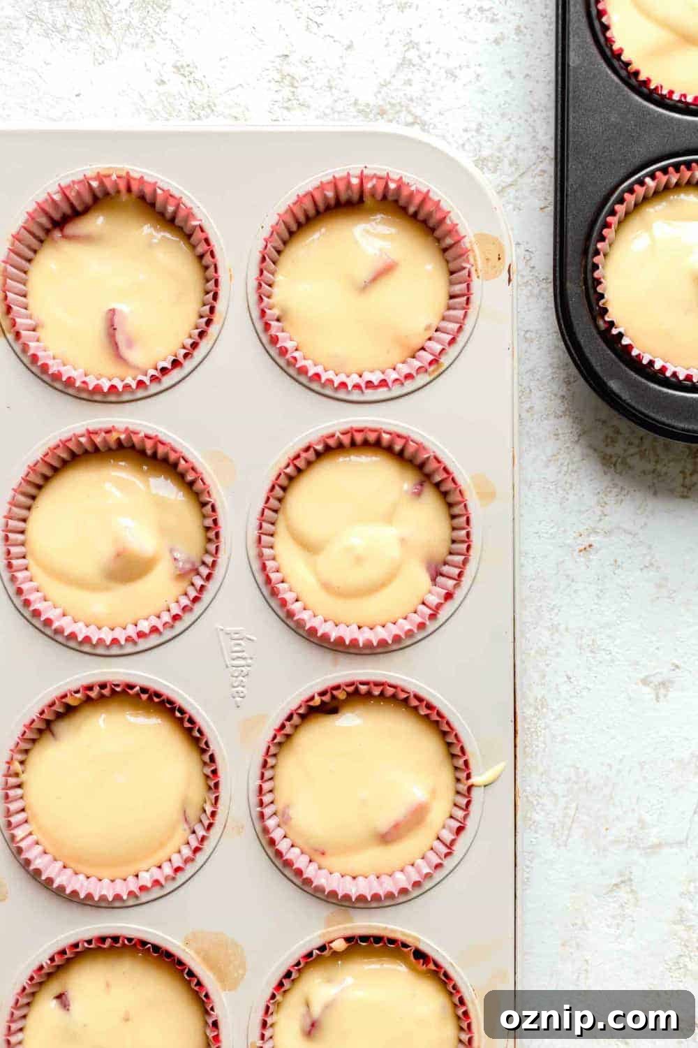 Overhead view of strawberry cupcake batter in red paper liners in cupcake pan