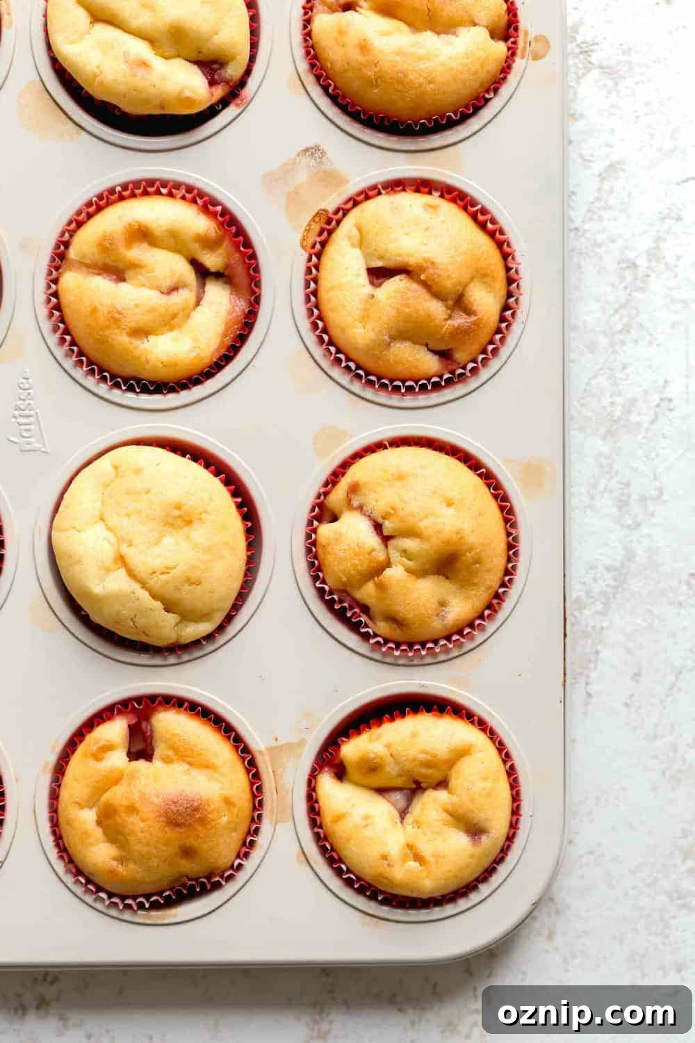 Overhead view of baked strawberry cupcakes in red paper liners in cupcake pan