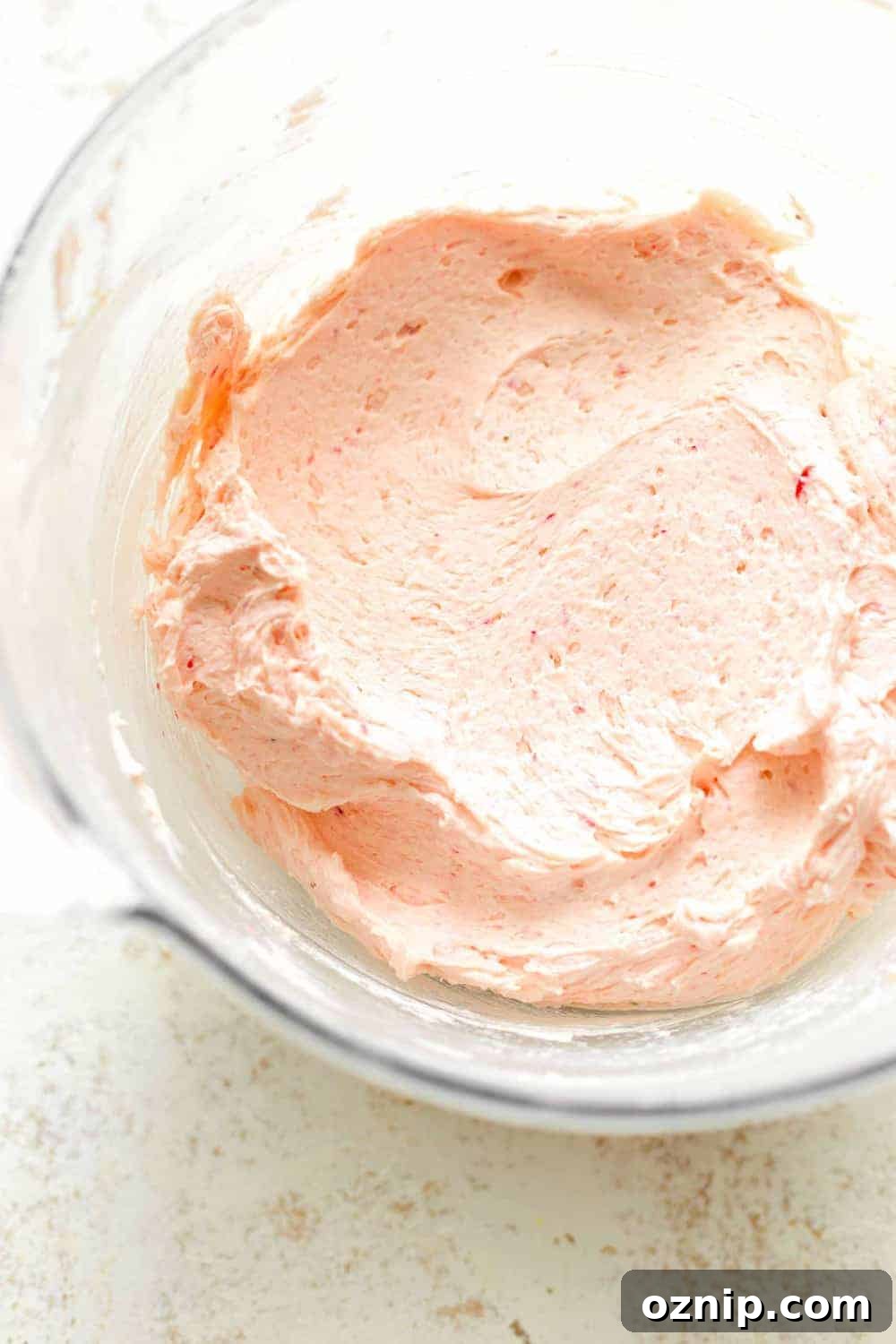 Overhead view of strawberry buttercream frosting in a glass bowl