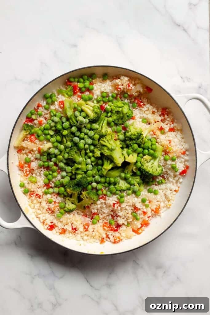 adding cauliflower rice, broccoli, and peas