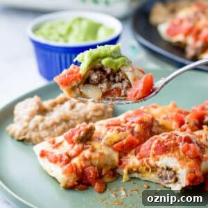 Cheesy Ground Beef Enchiladas with Red Sauce 10 A forkful of beef enchilada with guacamole over a plate