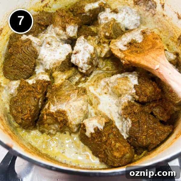 coconut milk being added to beef in a massaman curry paste.