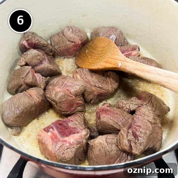 chunks of beef frying in a pan.
