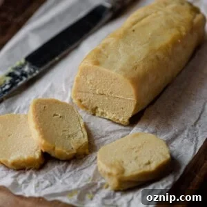 log of cashew cheese on parchment paper with knife.