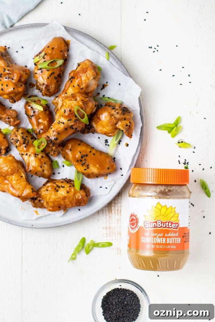 A plate of chicken wings next to a jar of SunButter sunflower seed butter.