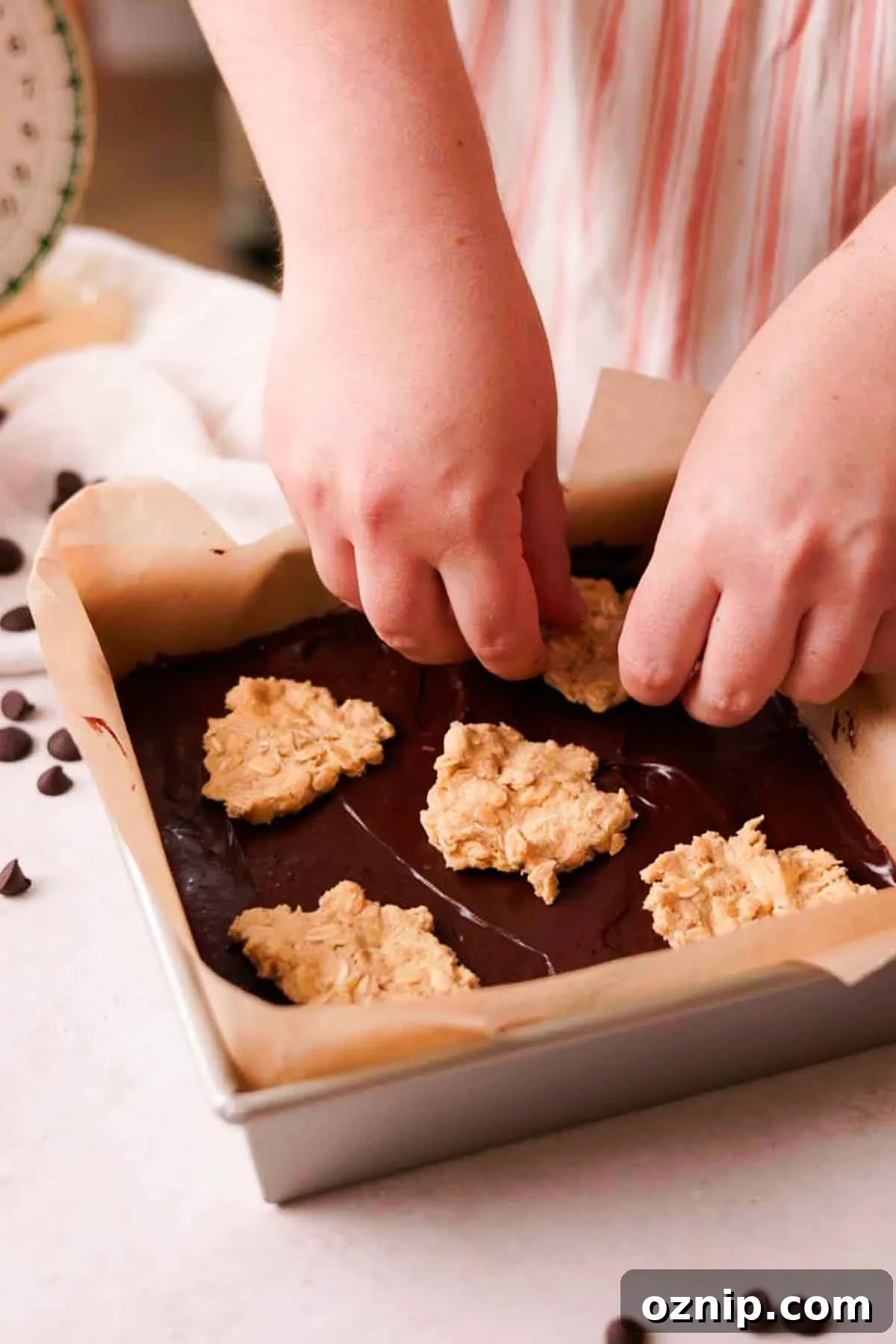 placing pieces of cookie dough on top of fudge in a pan