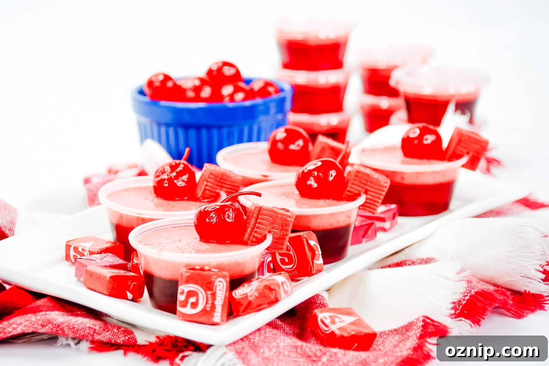 Cherry Starburst Jello Shots Recipe for Parties 4 a plate of cherry starburst jello shots garnished with a marachino cherry.