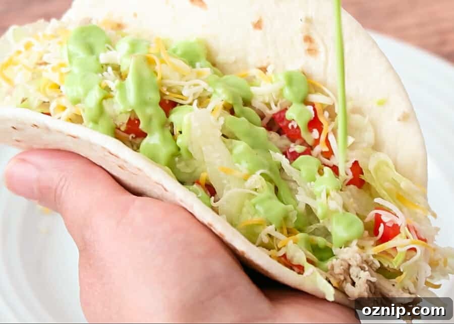 creamy avocado sauce being drizzled on a taco