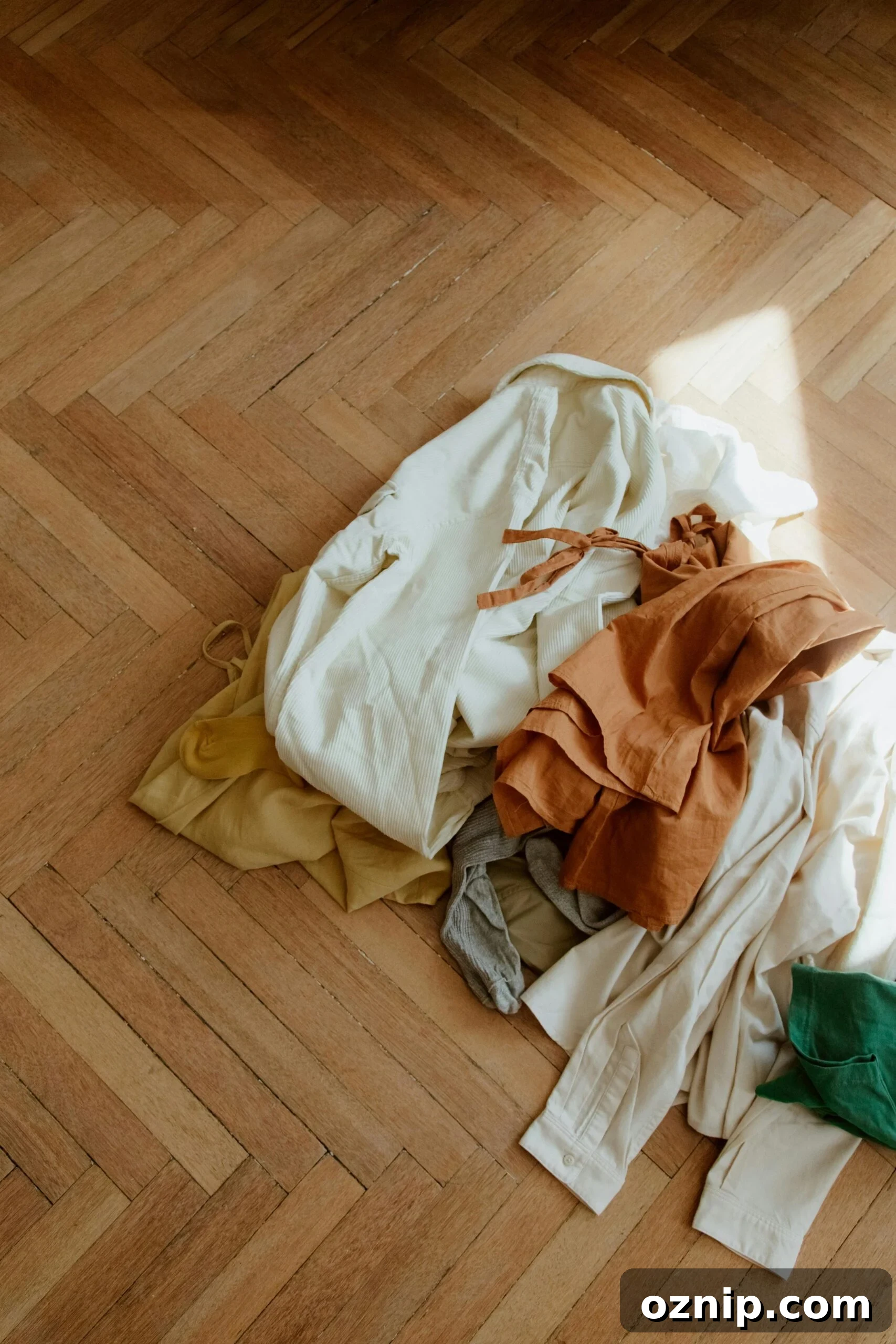 pile of neutral colored clothing on a wood floor