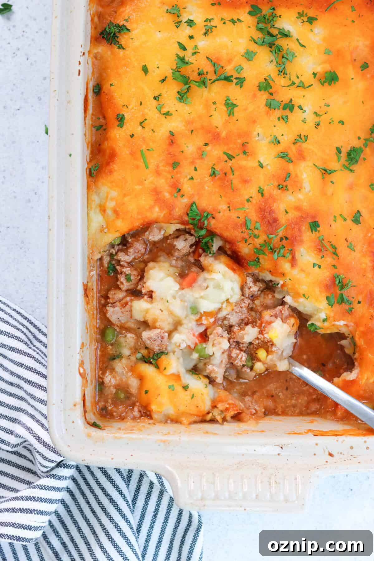 shepherd's pie in a casserole dish with a scoop being taken out