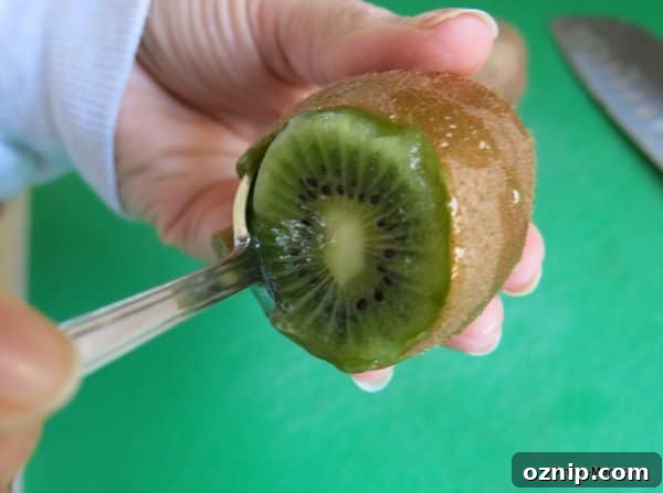 Low Sugar Apple Berry Salsa with Cinnamon Chips 5 spoon inside skin of kiwi demonstrating trick for taking skin off