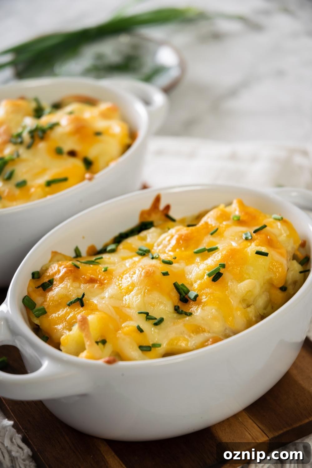 A white casserole dish filled with cheesy mashed potatoes.