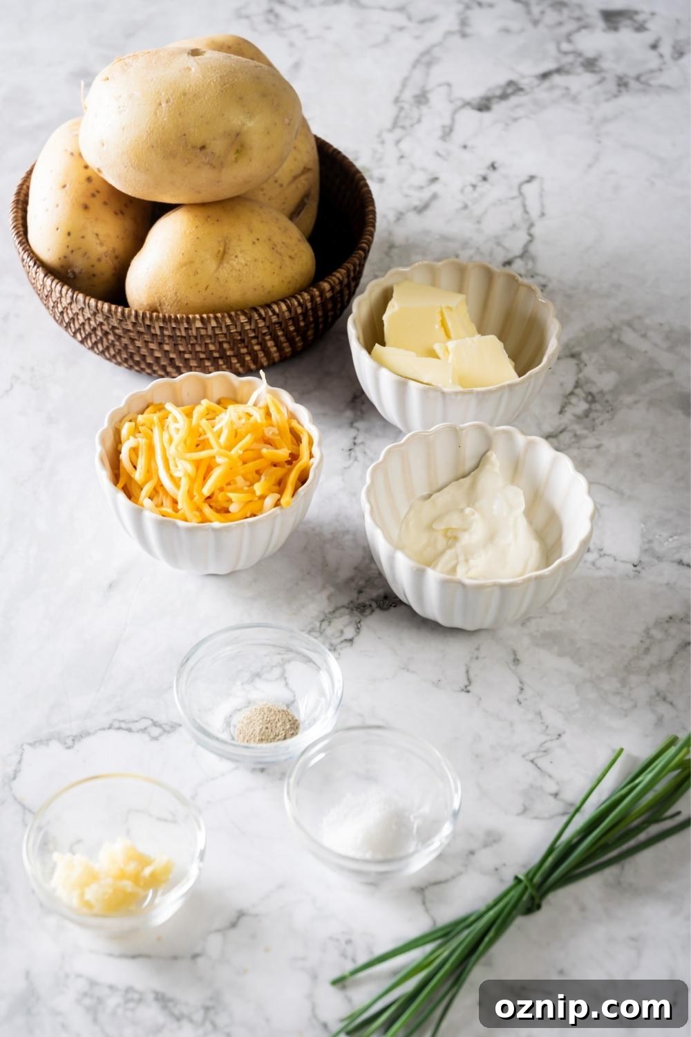 A bowl of potatoes, a bowl of cheddar cheese, a bowl of butter, a bowl of sour cream, a small bowl of salt, and a small bowl of pepper all on a white counter.