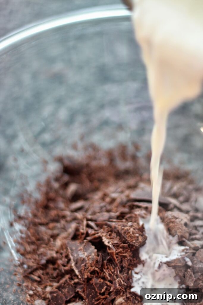 pouring hot cream over chopped chocolate in glass bowl